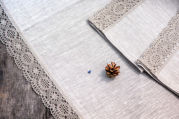 Shot of linen tablecloth and towels with lace trim and pine cone