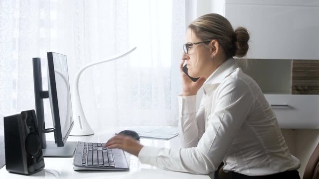 4k footage of smiling businesswoman talking by phone and browsing social media website on computer at office