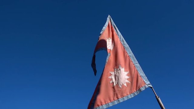 The national flag of Nepal moving on blue sky background on the way trekking to poon hill at Nepal