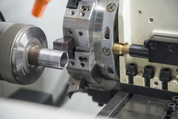 The CNC lathe machine cutting the thread of the pipe.