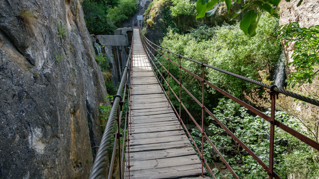 Iron and wooden suspension bridge in canyon between vertical rocks