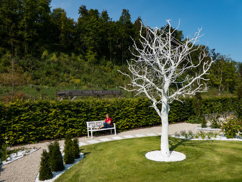 Kunst weißer Baum mit Frau auf Bank im Garten