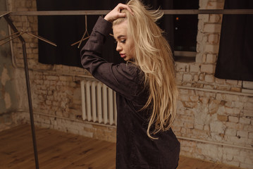 Obraz premium Young beautiful enjoys her beauty, photographs, and lunch. Full length of cheerful girl in black wearing crossed and looking up with smile while standing against grunge background