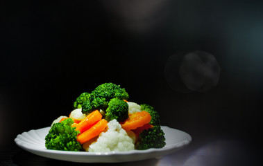Mixed vegetables. cauliflower, broccoli and carrots in plate on the old dark wooden background with copy space