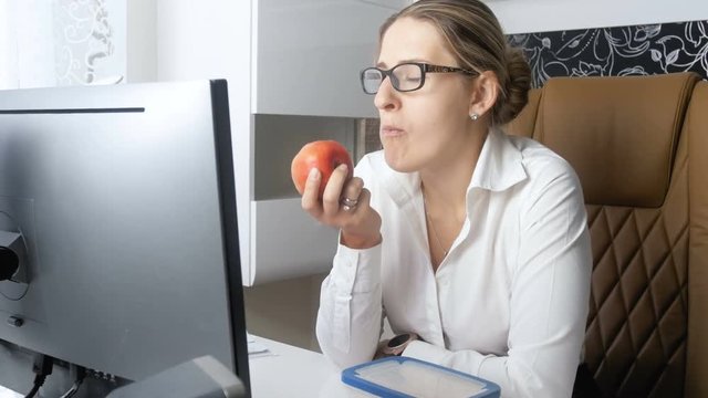 4k video of elegant businesswoman eating red apple in offce during lunch break