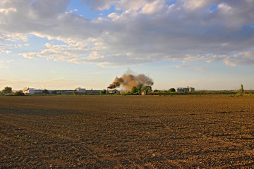 Black smoke from chimney and cornfield in front of the chimney