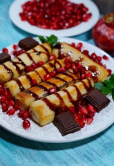Pancakes with white cheese, chocolate sauce, whole grain granatas and chocolate cubes. Tasty appetizing dessert

