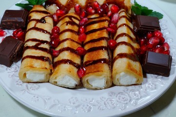 Pancakes with white cheese, chocolate sauce, whole grain granatas and chocolate cubes. Tasty appetizing dessert
