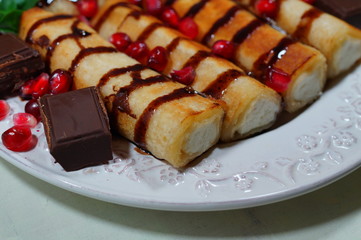 Pancakes with white cheese, chocolate sauce, whole grain granatas and chocolate cubes. Tasty appetizing dessert
