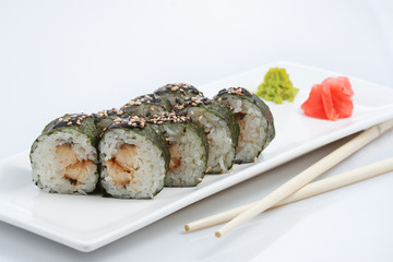 sushi or rolls on a long plate, wooden sticks, red ginger and wasabi