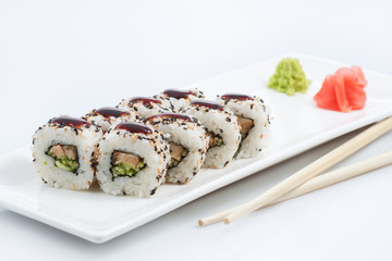 sushi or rolls on a long plate, wooden sticks, red ginger and wasabi