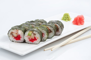 sushi or rolls on a long plate, wooden sticks, red ginger and wasabi