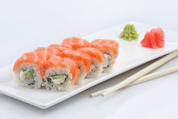 sushi or rolls on a long plate, wooden sticks, red ginger and wasabi