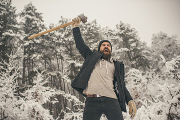 bearded man lumberjack hold axe in snowy winter forest, camping