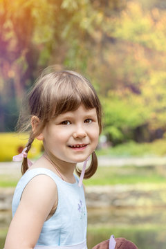 Cute little girl plaing in the city park on a summer sunny day. Portrait little girl close up, big brown eyes. Toned photo.