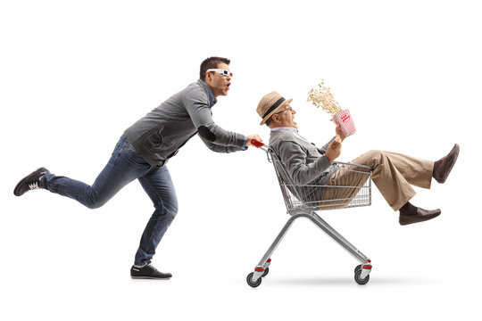 Young man with 3D glasses pushing a shopping cart with a mature man with popcorn riding inside