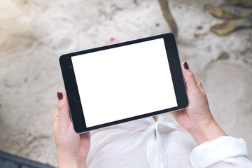 Mockup image of a woman's hand holding black tablet pc with blank white desktop screen with sand and beach background