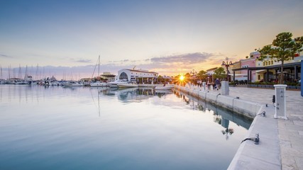 Beautiful Marina, Limassol city Cyprus. Modern, high end life in newly developed port with docked yachts, restaurants, shops, a landmark for waterfront promenade. View of the commercial area at sunset - obrazy, fototapety, plakaty