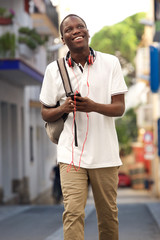 young man walking on street with bag and mobile phone