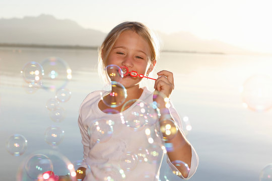 Young girl, outdoors, blowing bubbles