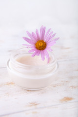 Obraz na płótnie Canvas face-cream and flower on a white wooden background. natural organic cosmetic facial.
