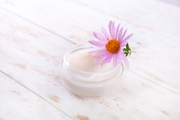 Fototapeta na wymiar face cream with blossom on white wooden table natural organic cosmetic facial. space for text