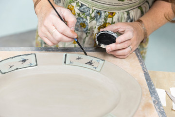 Potter painting motifs on platter