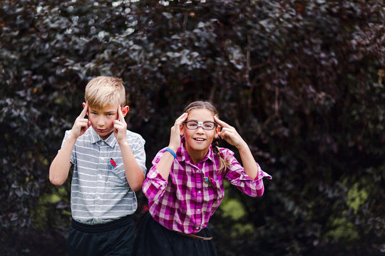 Siblings dressed up as nerds, hands on head looking at camera