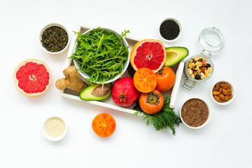 Healthy food in wooden tray: fruits, vegetables, seeds and greens on white background. Flat lay. Top view