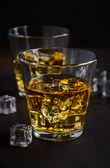 Glass of whiskey with ice on dark background Selective focus 