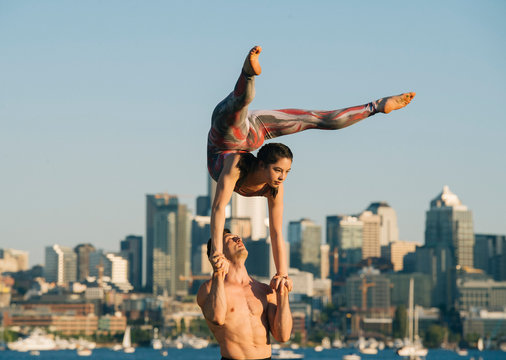 Teenage girl and young man, outdoors, woman balancing on man's hands in yoga position