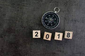 Year 2018 prediction or direction concept with compass and wooden block number 2018 on dark black background