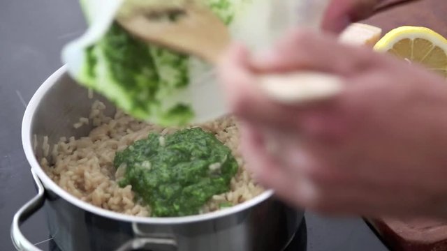 Risotto kochen auf modernem Herd, Detailaufnahme, Video HD 1080, Pesto wird eingerührt, Zeitraffer