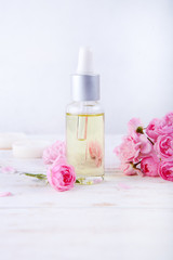 Obraz na płótnie Canvas Spa setting with pot of moisturizing cream beautiful pink roses and rose oil on white background