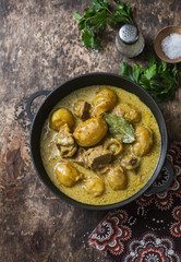 Beef potato massaman curry in a frying pan on wooden background, top view. Comfort, delicious food in the asian style