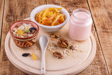 Healthy breakfast. Ceramic bowl with oat flakes, dried fruits, nuts on wood background