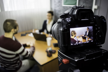 camera on the set of a business meeting between a man and a woman