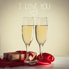 Two glasses with champagne, a wrapped gift and a red ribbon. Added the inscription I love you