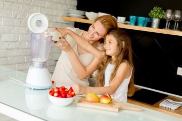 Obraz na płótnie Canvas Mother and daughter preparing healthy juice