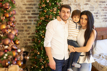 A young family in the apartment decorated for Christmas