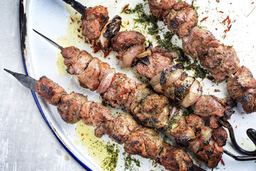 Traditional Russian shashlik on a barbecue skewer with roasted onion as top view on white tray