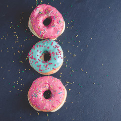 Donuts with colorful icing on a dark background.