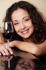 Happy young woman smiling at the bar counter with a glass of red wine