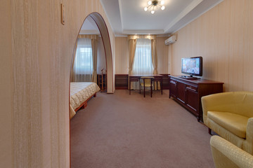 A hall in the bedroom, with easy yellow chairs, a desk and the TV set