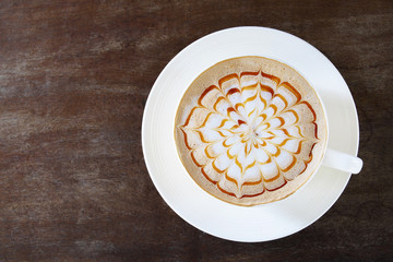 Top view of hot coffee caramel macchiato cappuccino cup on old wood table background.