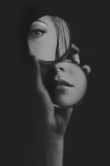 Woman looking at her eye and mouth in small mirror artistic conversion - 186888602