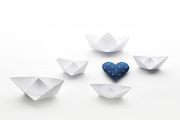 paper boats on a white matte background and heart with an anchor