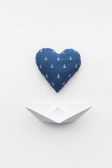 paper boats on a white matte background and heart with an anchor