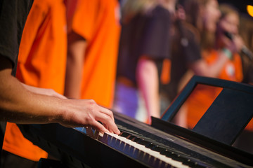 Male musician plays a musical instrument on the stage. Artist playing on the keyboard synthesizer...