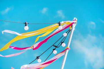 Colorful ribbons and festival lights on clear blue sky summer background 